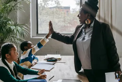 Two professional women high-fiving across a meeting room table